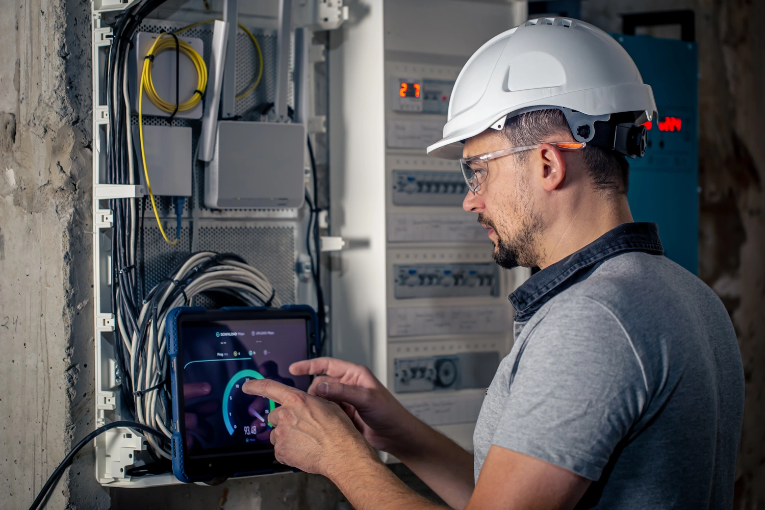 Med Prüfservicre – Anbieter von Elektrogeräten – Ergebnis: Elektrotechniker arbeitet an einer Schalttafel mit Sicherungen und verwendet ein Tablet